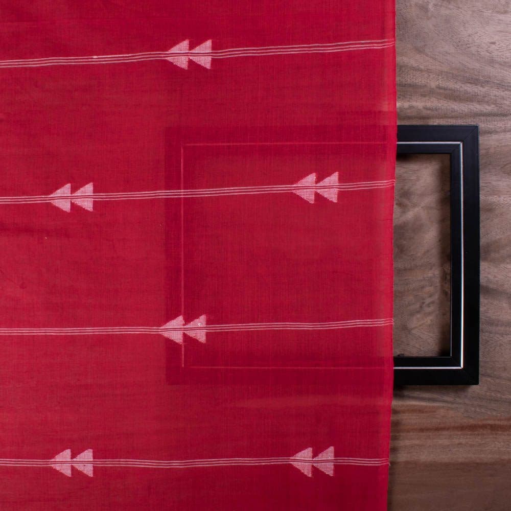 Full-width view of red plain cotton Jamdani fabric with repeating white arrow motif pattern
